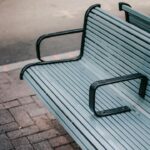A modern city bench with metal arm dividers, symbolizing hostile architecture and exclusion in urban design.