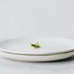 Grasshopper on minimalist plate for advanced English lesson about eating insects and food psychology