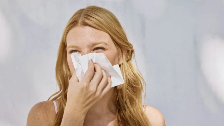 Woman blowing her nose with a tissue, illustrating runny nose symptom vocabulary in this A2 ESL lesson plan on feeling sick.