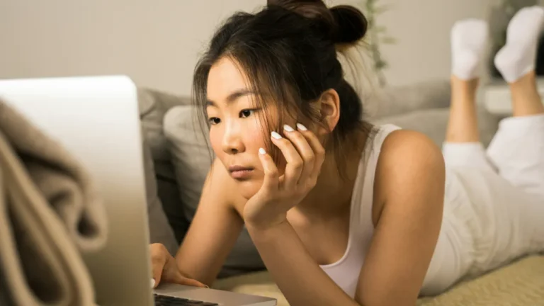 Woman looking bored while watching a laptop screen, cover image for the Watching YouTube A2 lesson on betterclass.net
